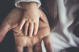 A baby's hand on top of an adults hand.
